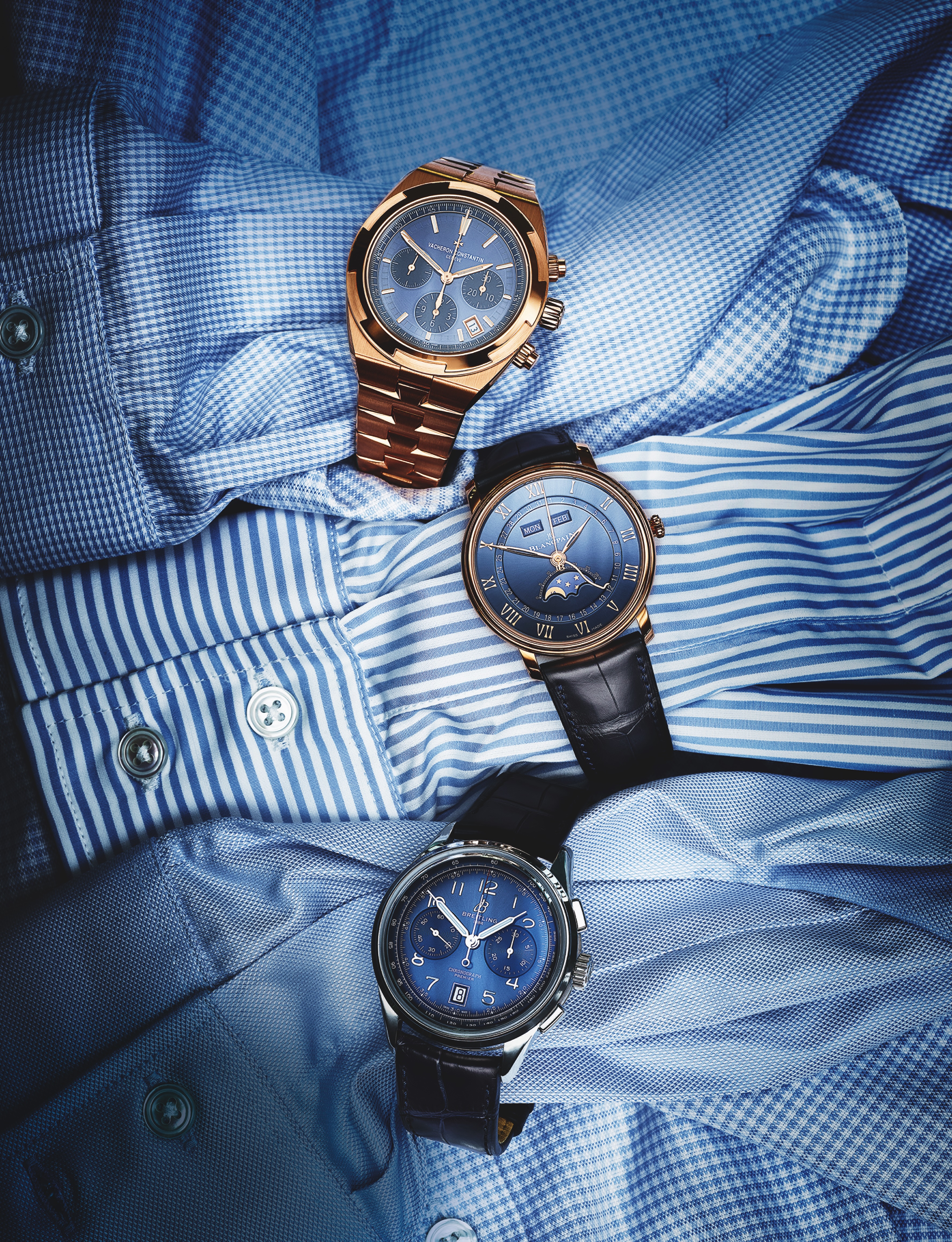 Flatlay-style shoot of three watches wrapped around three blue cotton shirt sleeves