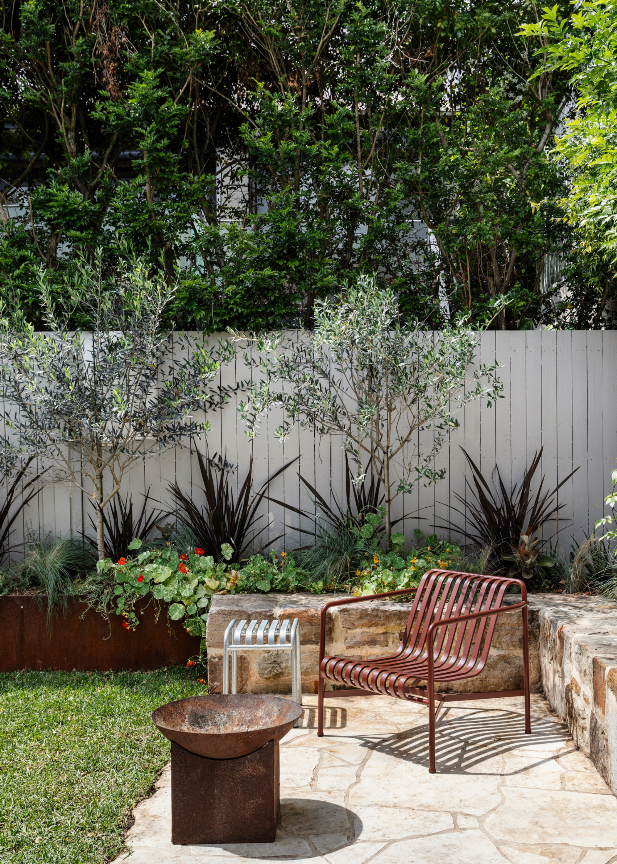 A backyard with metal furniture and a pedestal fireplace