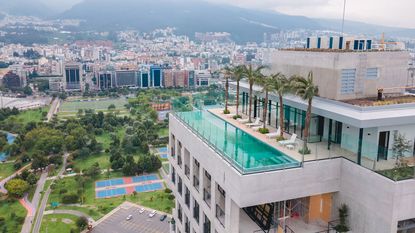 Qorner penthouse pool with palm trees and view of Quito