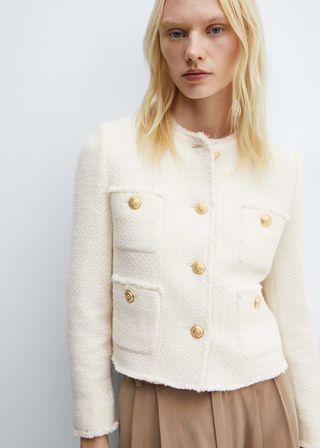 model wears jacket with golden button and khaki pleated skirt 
