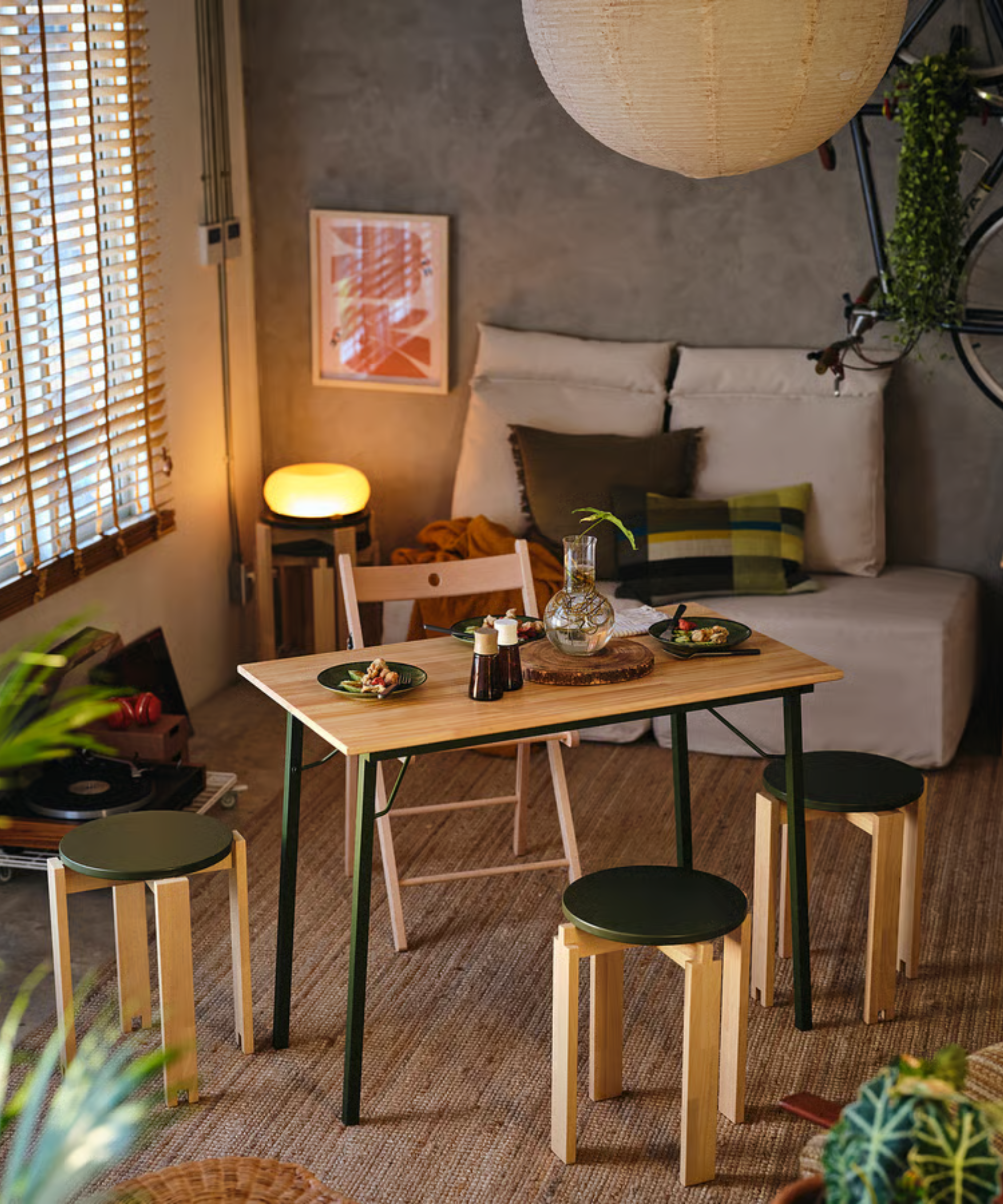 an apartment room with a folding table, several stools, and a makeshift couch against the wall
