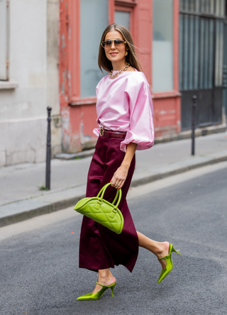 Nina Sandbech wears burgundy skirt and pink top homemade, green heels Prada, green bag Mietis, sunglasses Loewe during Womenswear Spring/Summer 2025 as part of Paris Fashion Week on September 29, 2024 in Paris, France