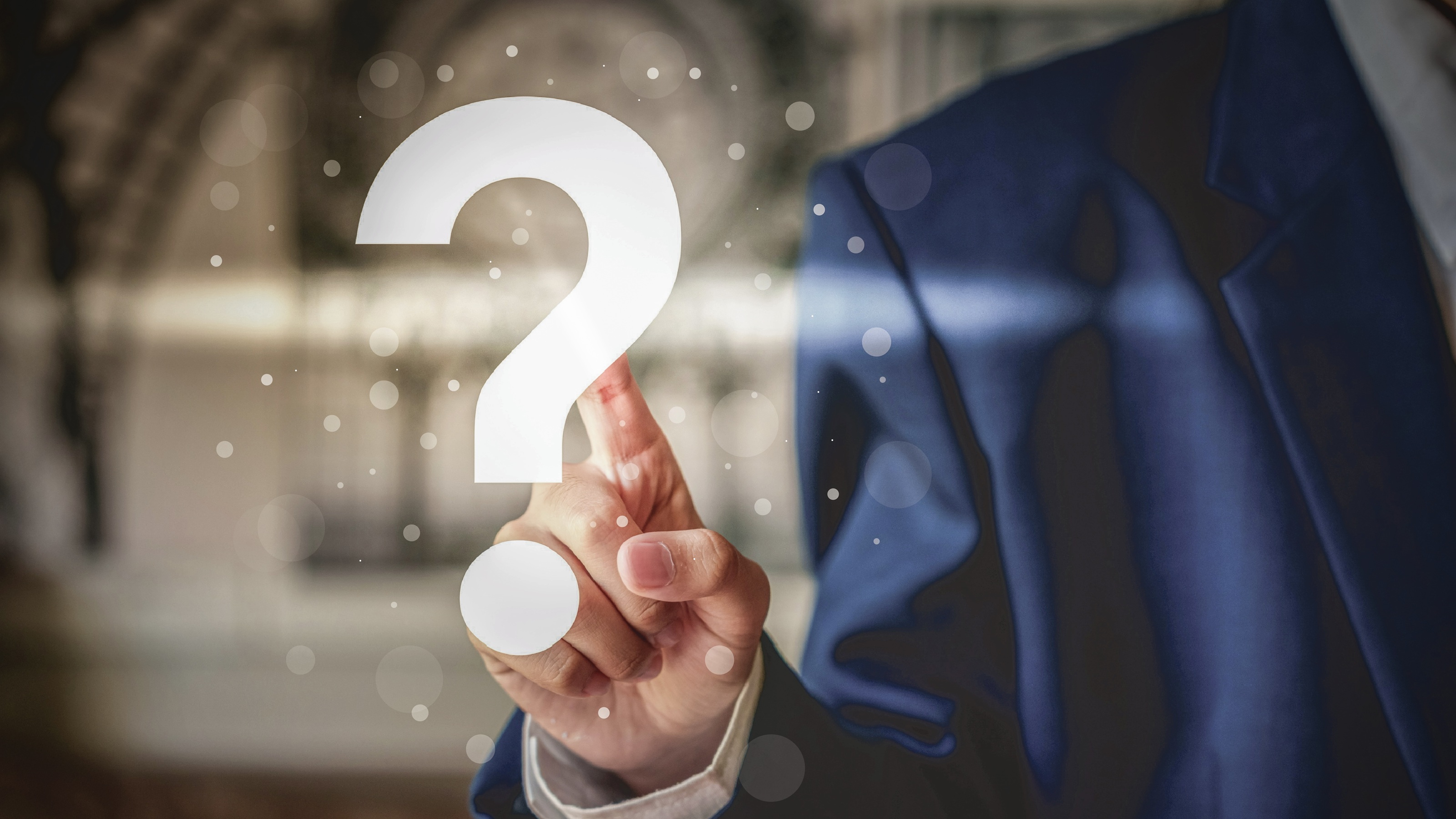 A businessperson touches a finger to a large white question mark.