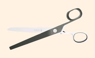 A pair of open scissors against a pink background