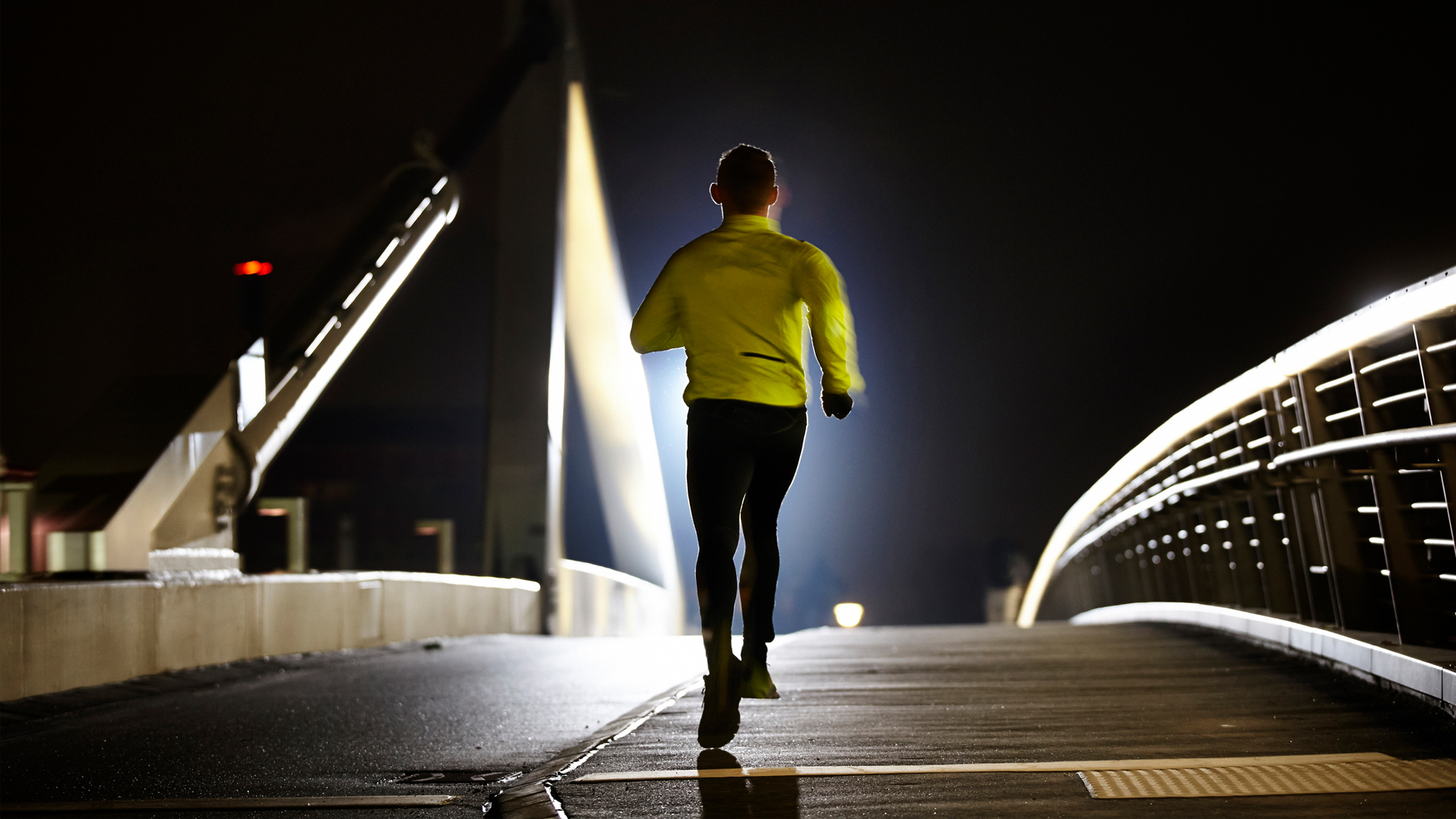 man running across a bridge at night