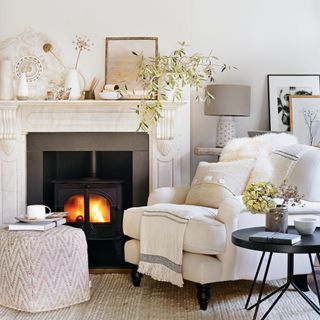 White living room with fireplace, armchair and foorstool