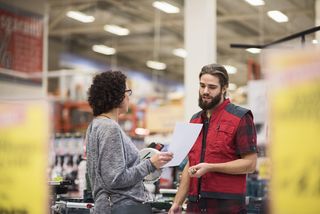 A woman talking to a man in a red gillet inside a home improvement store