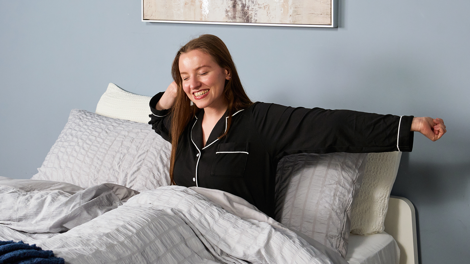 Sleep tester Frances Daniels wakes up in bed and stretches after a good night's sleep