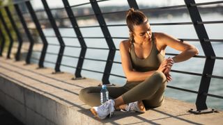 Woman sitting on wall checking GPS watch