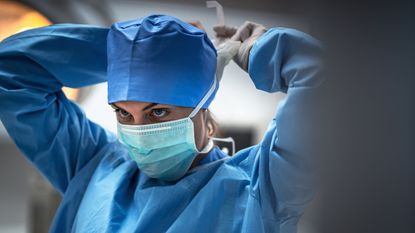 A surgeon puts on a surgical mask.