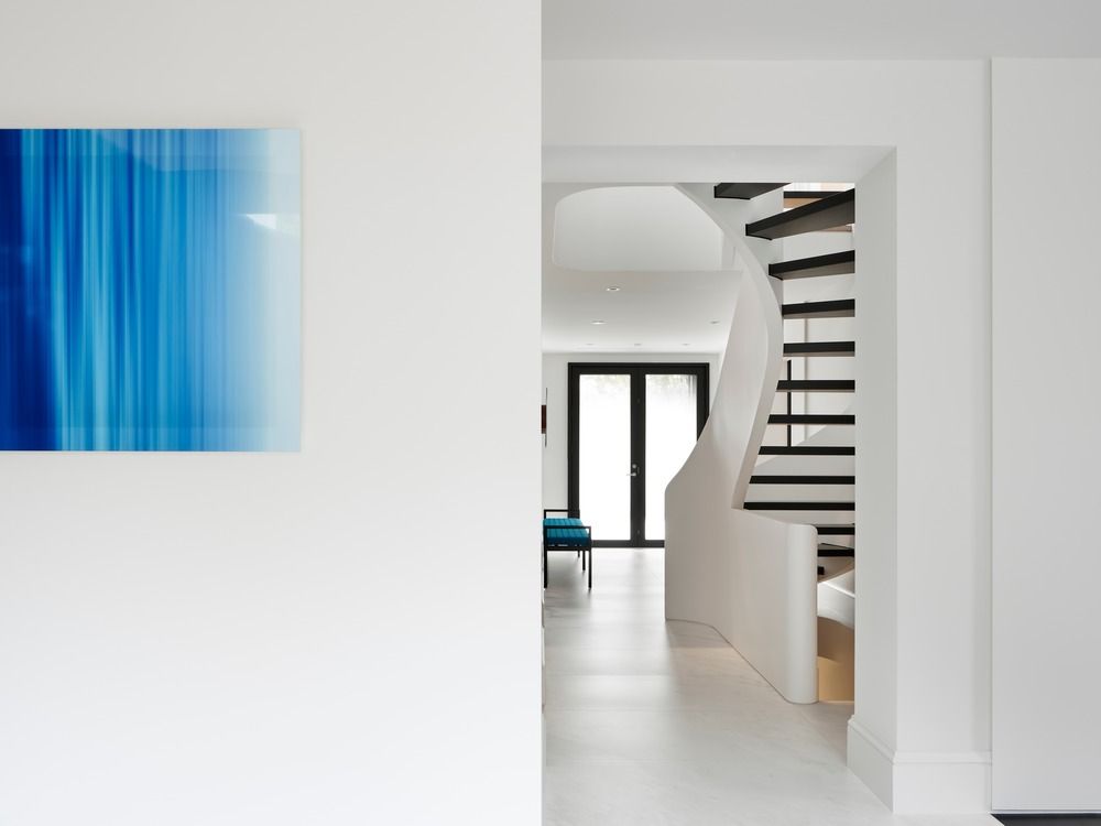 White hallway with white curved staircase and black steps