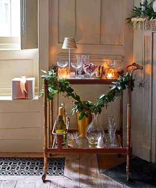 Close up of gold drinks trolley dressed with foliage, candles, lamps and drinksware