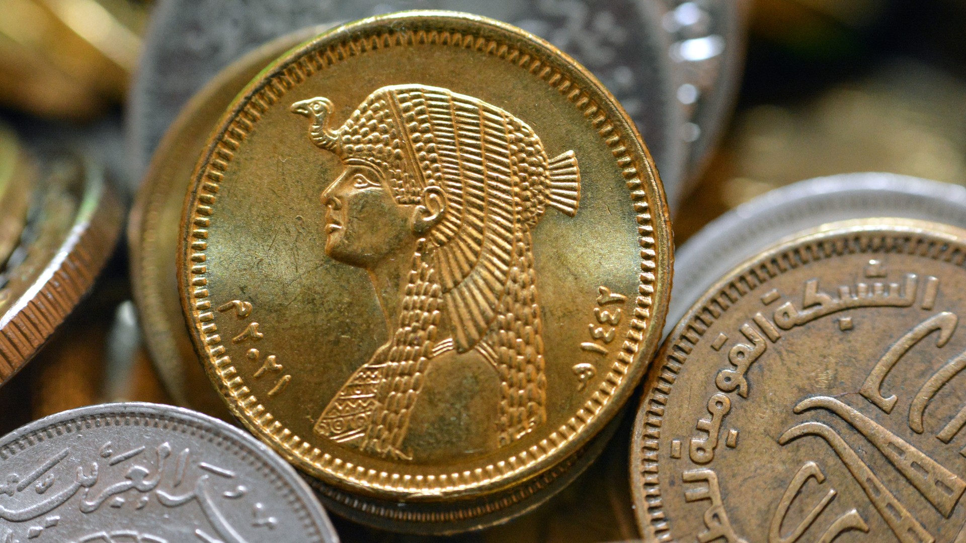 The obverse of the Egyptian 50 fifty piastres AD 2021, 1442 AH, on a blurred background of several coins, circulating Egyptian coins on a background with the slogan of Queen Cleopatra.