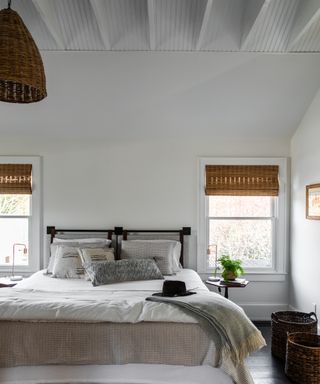 white bedroom with oversized wicker pendant and black bed