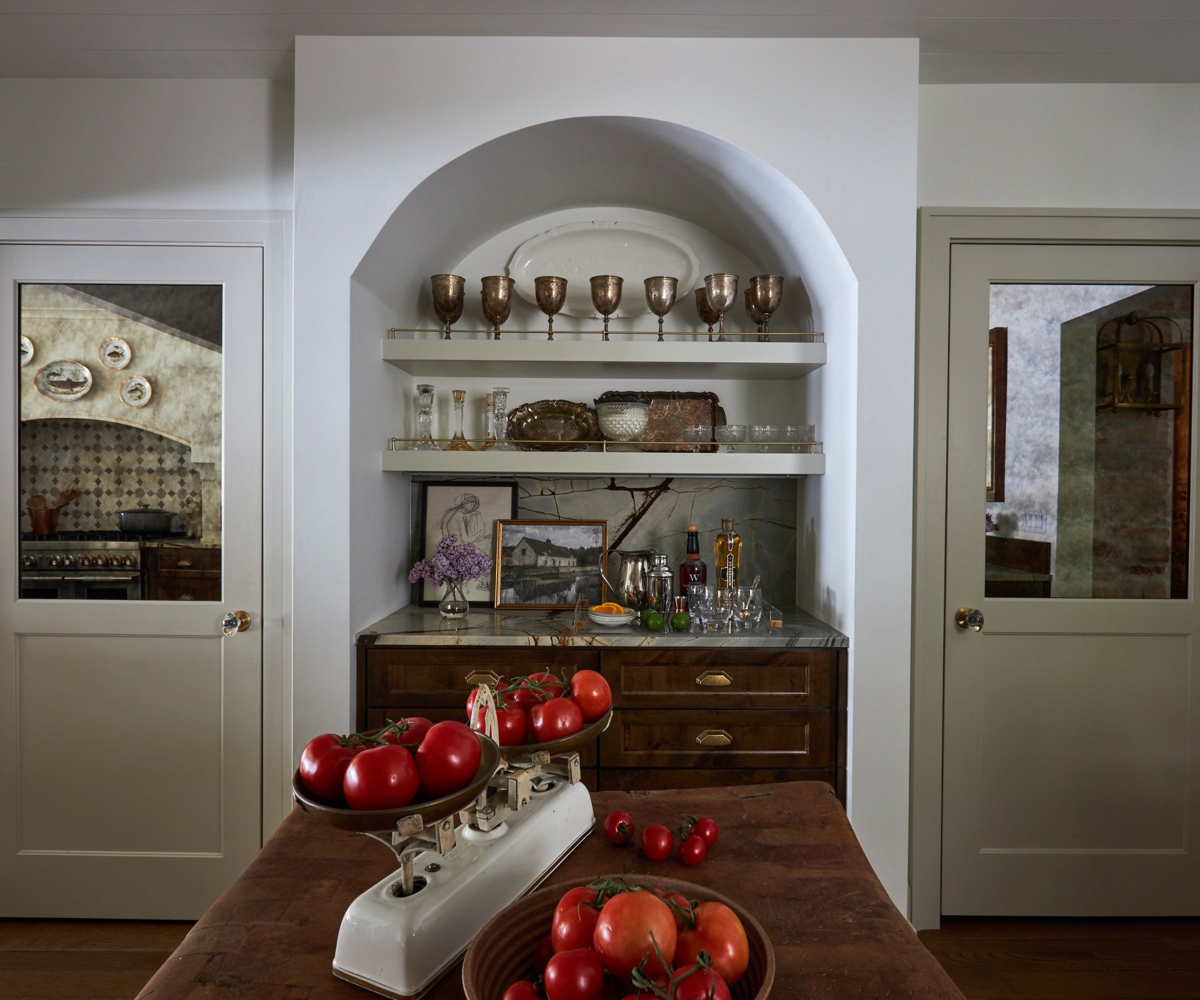 A Nora Ephron-inspired kitchen with alcove shelving and a cabinet decorated with kitchenware and art