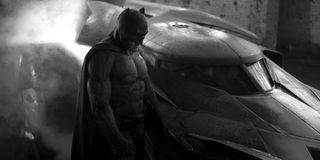 Batman looking dour next to the batmobile