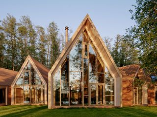 the lake house, a timber structure in a forest, made up of a cluster of volumes with pitched roofs