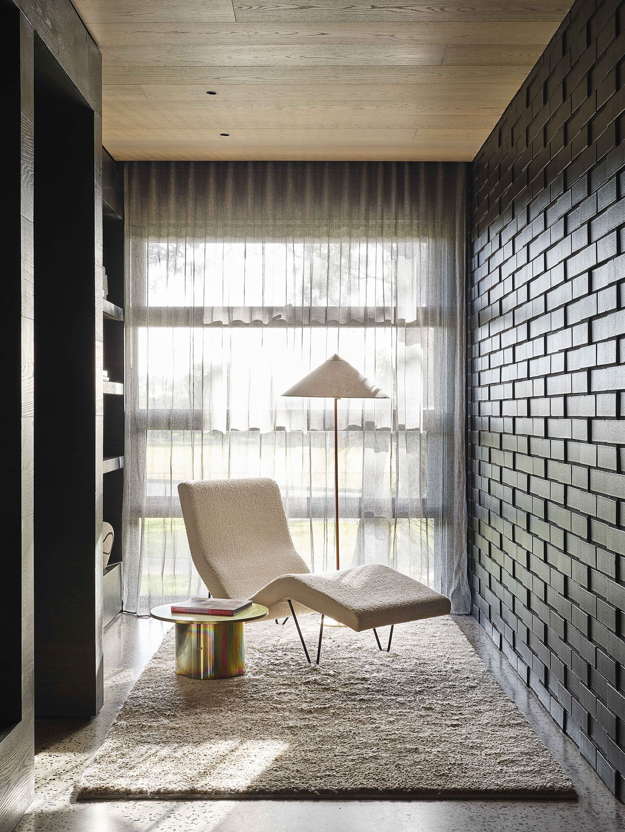 A lounge chair next to a large window creating an intimate seating area