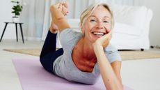 An older woman demonstrates her flexibility by grabbing her foot from behind