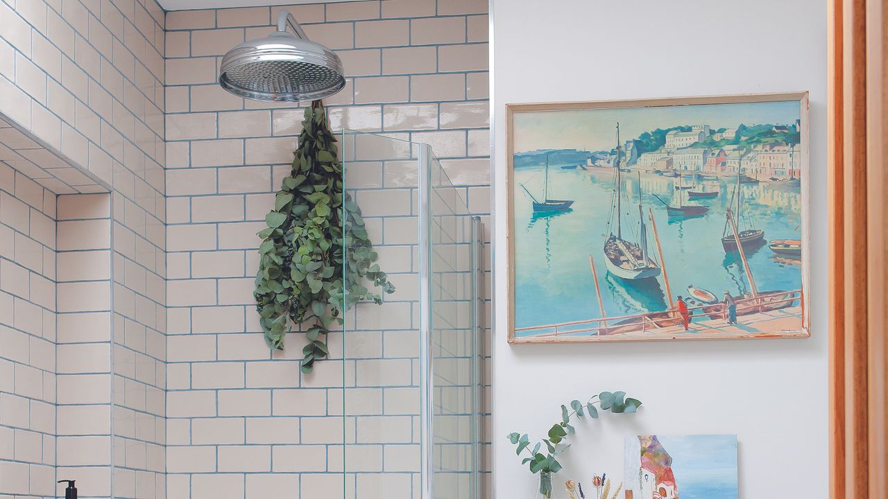 Bathroom with shower, eucalyptus hanging and art on wall.