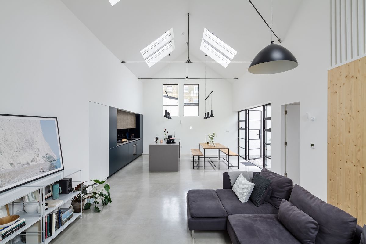 Polished concrete floors, white walls, steel-framed Crittal-style windows and sections of spruce panelling sit in harmony within the open plan double-height kitchen/dining/living space.