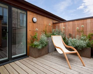 modern urban balcony garden with potted plants and reclining chair