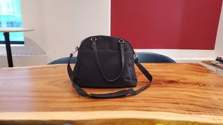 a black overnight bag sitting on a wooden desk