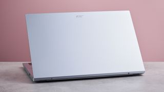 Three-quarter view of rear of Acer Aspire Go 15 open on desk, with pink wall in background