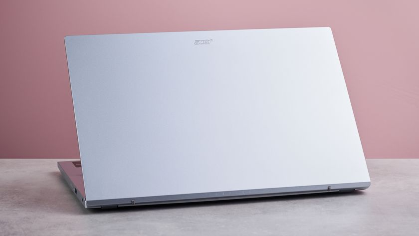 Three-quarter view of rear of Acer Aspire Go 15 open on desk, with pink wall in background