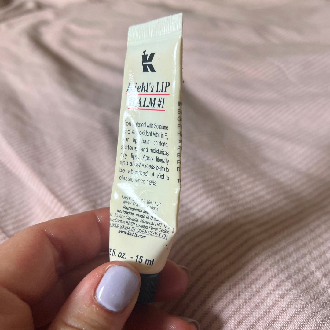 Hand holding empty white tube of Kiehl's Lip Balm #1