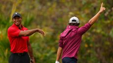 Tiger celebrates with son Charlie after he chips-in, with Charlie raising his hand in the air