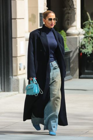 jennifer lopez wearing turtleneck, coat, jeans, handbag, and heels