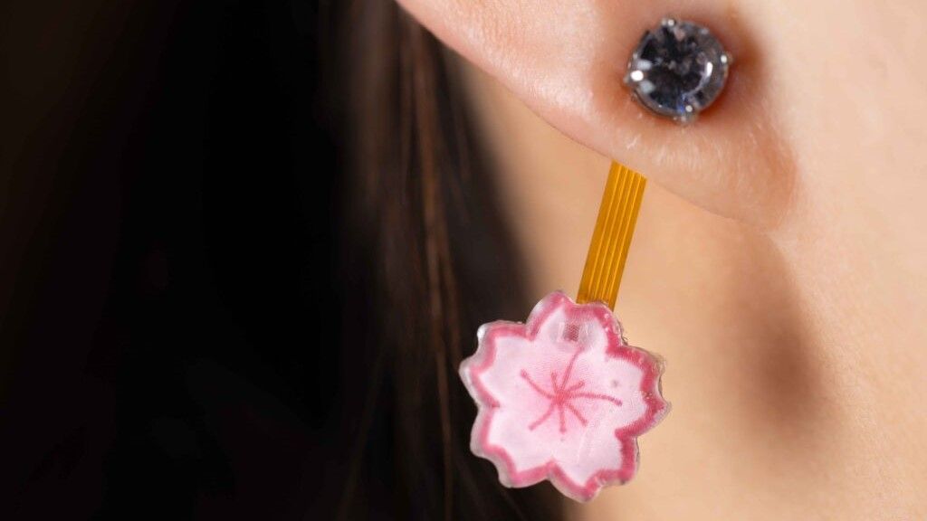 The Thermal earring in a person&#039;s right ear with a flower hiding the circuit board