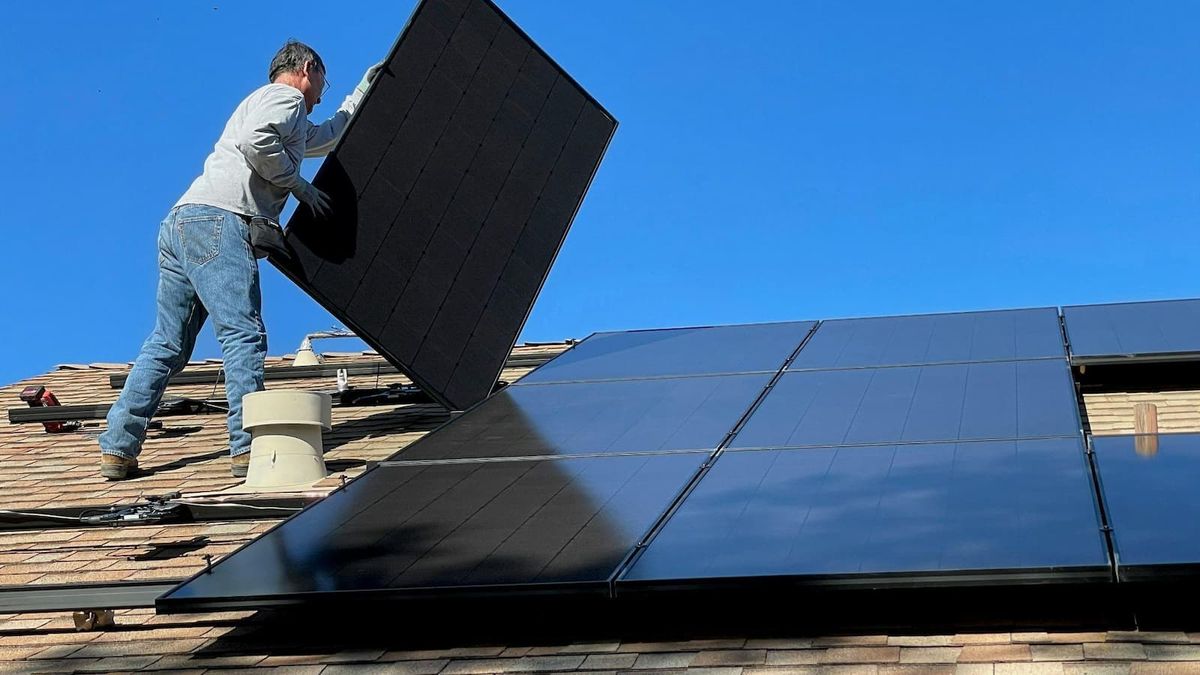 A man installing a solar panel on a roof