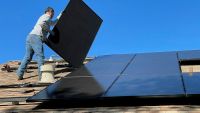 A man installing a solar panel on a roof