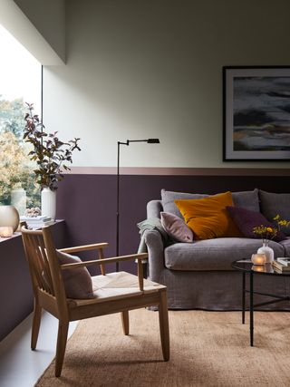 living room with purple eggplant paint on dado rail, grey sofa, artwork, white floor, textured rug