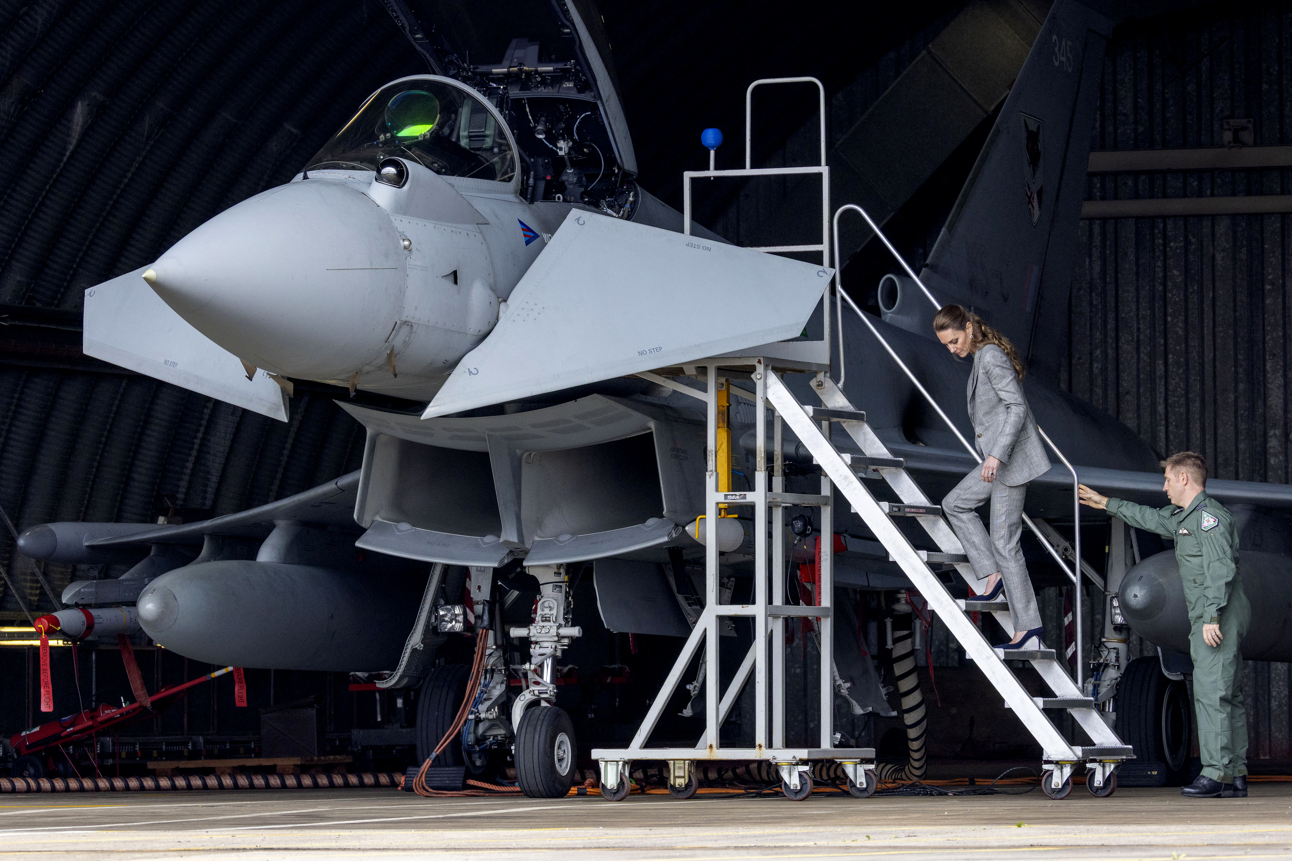 Kate Middleton climbing a plane in a gray suit