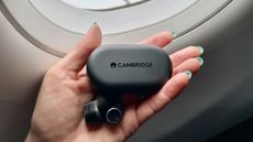 Cambridge Audio Melomania M100, held in a hand with blue fingernails, in the window of an aircraft