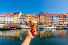 Eating multi-colored ice cream with colourful vibrant houses of Nyhavn harbour in background, Copenhagen, Denmark