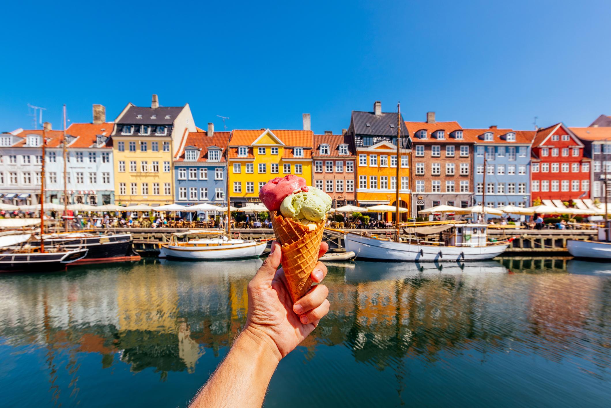  Eating multi-colored ice cream with colourful vibrant houses of Nyhavn harbour in background, Copenhagen, Denmark 