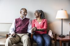 A seated couple holding hands looking at each other