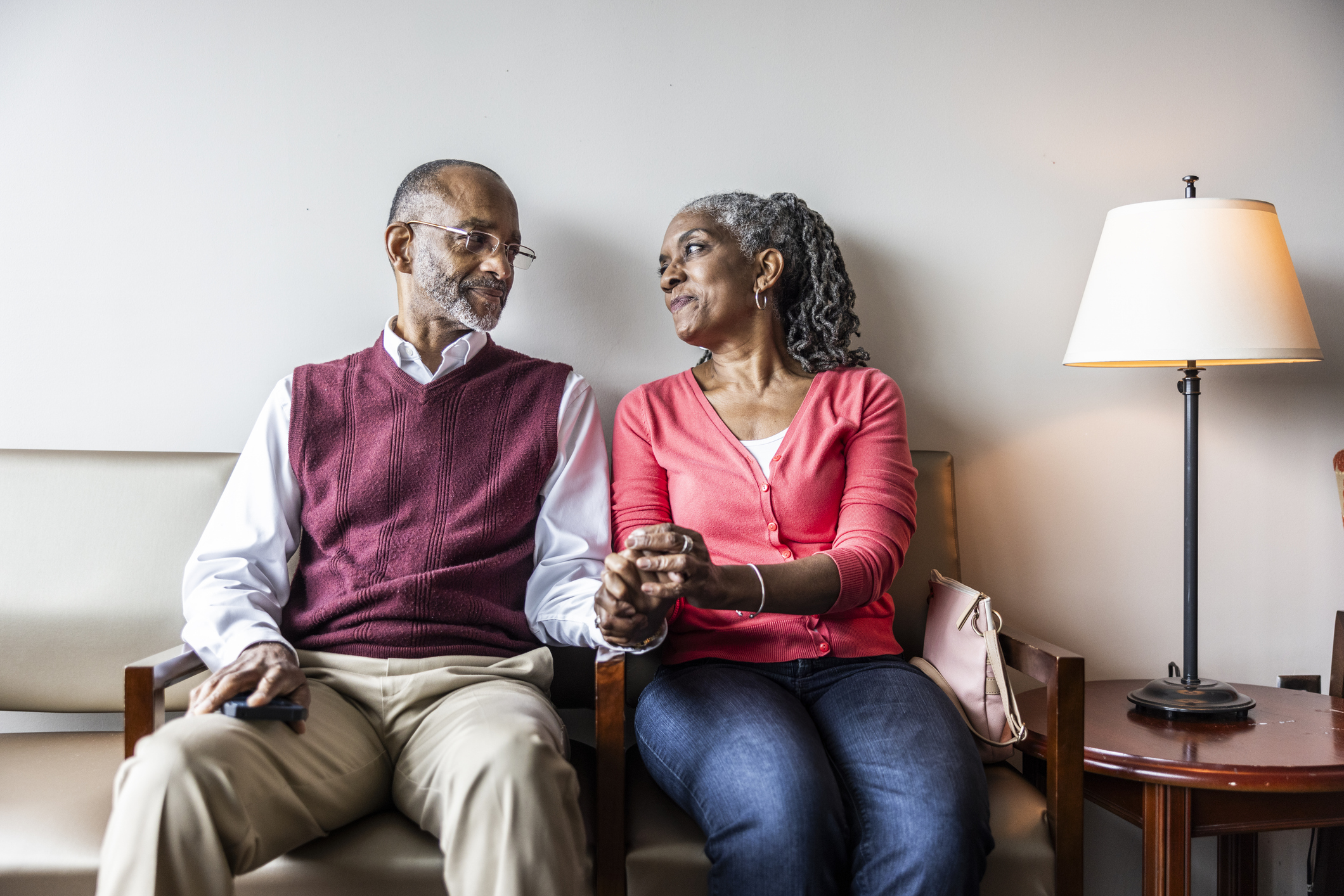 A seated couple holding hands looking at each other