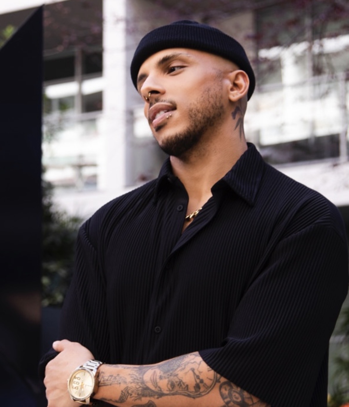a man with tattoos in a black shirt and hat