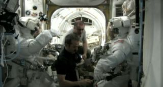 NASA astronauts Chris Cassidy and Tom Marshburn don their NASA-issue Extravehicular Mobility Units for an emergency spacewalk to find an ammonia link outside the International Space Station. Canadian astronaut Chris Hadfield (center) and Russian cosmonaut Pavel Vinogradov assist in the May 11, 2013 spacewalk work.