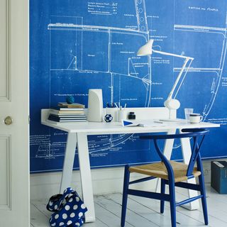 room with blue board on wall and wooden floor and white desk with blue chairs