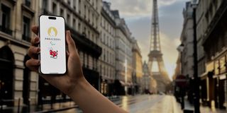 An image of a phone with the Paris Olympics logo on it in front of the Eiffel Tower 