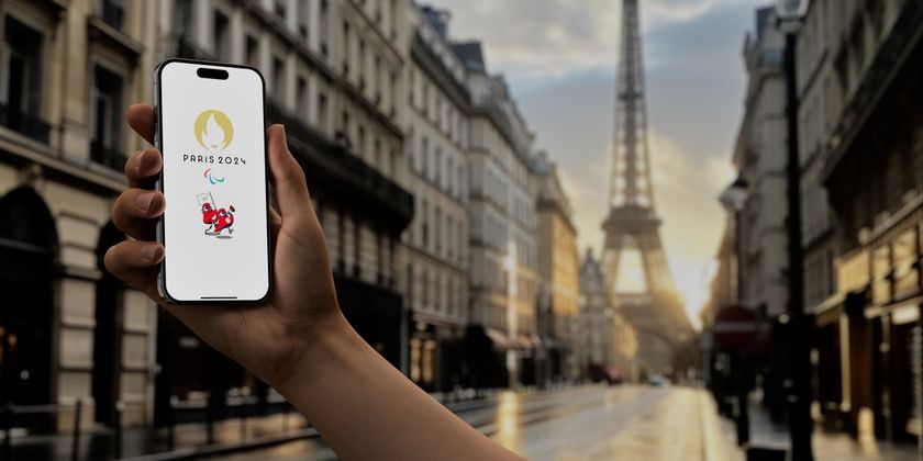 An image of a phone with the Paris Olympics logo on it in front of the Eiffel Tower 