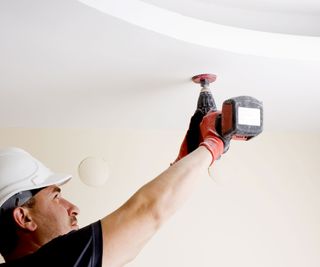 Man drilling hole in ceiling with a hole saw bit