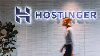 Hostinger logo on a wall with a lady captured walking by
