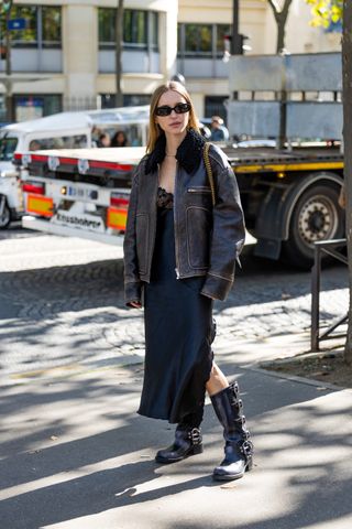 Pernille Teisbaeck wears shearling brown black jacket, black silk dress with lace top, Balenciaga bag outside Miu Miu during Paris Fashion Week - Womenswear Spring/Summer 2023 : Day Nine on October 04, 2022 in Paris, France.